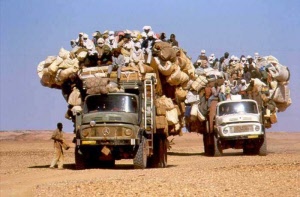Von Menschen überfüllte Lastwagen in der Wüste